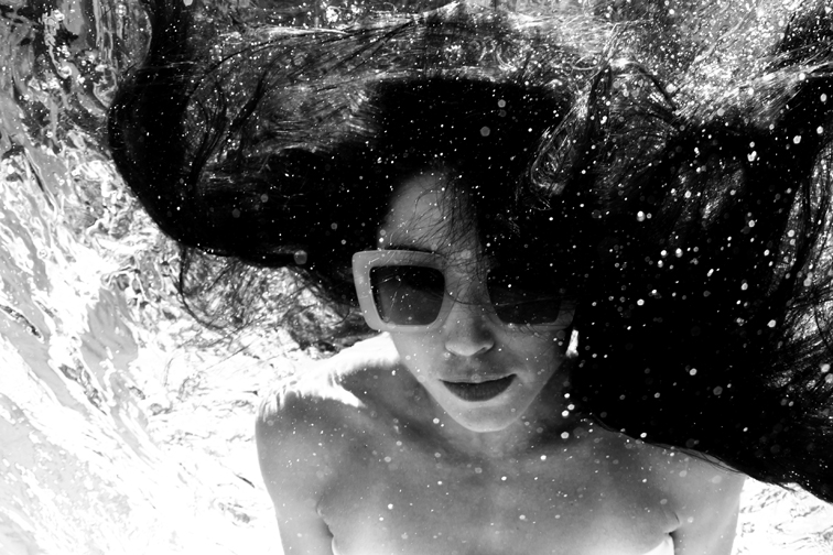 Jeune femme sous l'eau cheveux flottants avec des lunettes de soleil LAPIMA