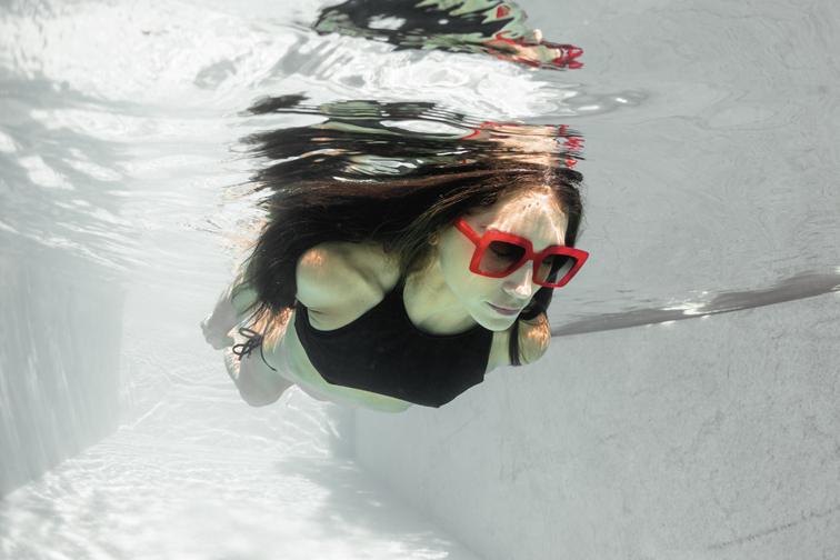 Jeune femme nageant sous la surface de l'eau avec des lunettes de soleil LAPIMA