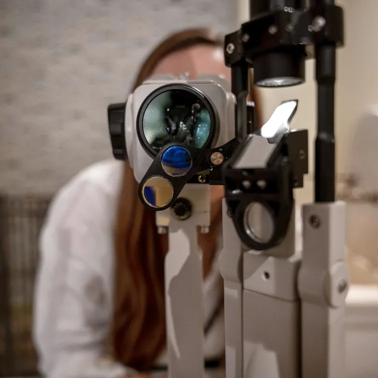 Photo d'un opticien derrière son microscope d'examen de vue