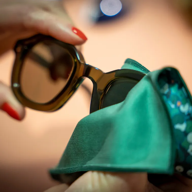 Photo des mains d'une opticienne nettoyant des verres