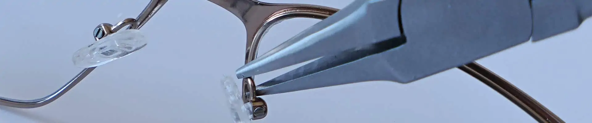 Bannière de page Expertise des opticiens indépendants Eye-Like. Photo du travail sur des lunettes à l'aide d'une pince